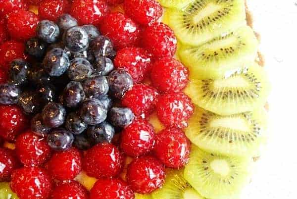 Blueberries, raspberries, and kiwi slices on a tart.