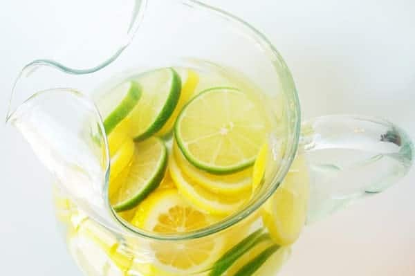 Top view of a glass pitcher with lemon and lime slices and clear punch.