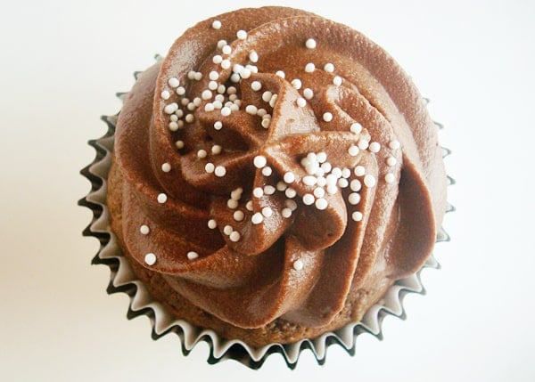 Top view of a chocolate frosted cupcake with white sprinkles.