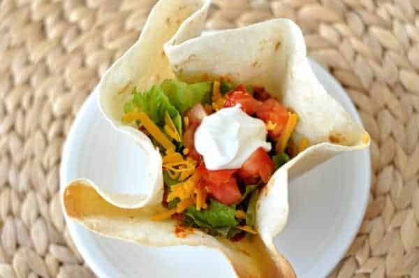 Top view of a tortilla bowl filled with taco meat and toppings.