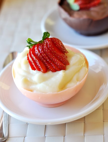 Round chocolate cup filled with vanilla pudding and topped with sliced strawberries.