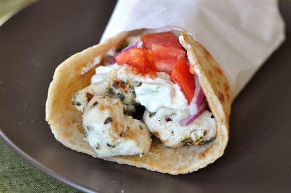 Wrapped chicken gyro on a black plate.