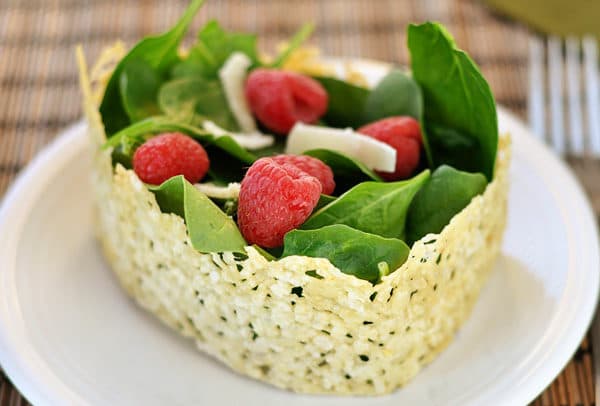 A spinach and raspberry salad in a ring of crisped asiago cheese.