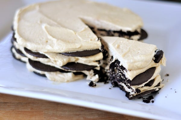 A chocolate and peanut butter wafer cream cake with a slice cut out all on a white platter.