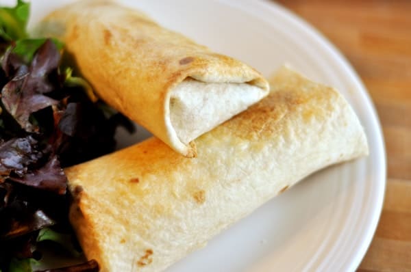 Two baked chimichangas on a white plate.