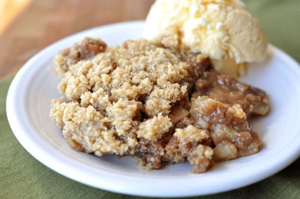 Apple cider pudding cake and a scoop of vanilla ice cream on a white plate.