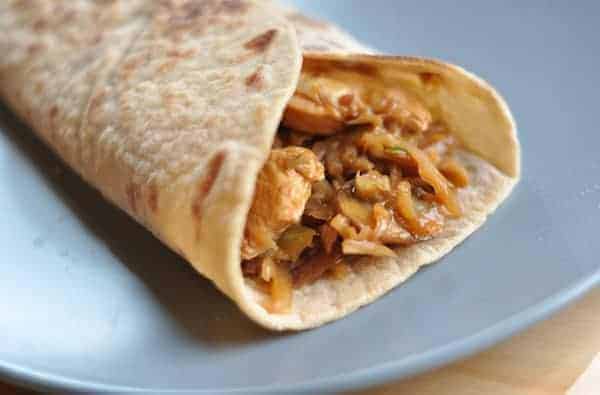 White tortilla with asian chicken mixture inside on a blue plate.
