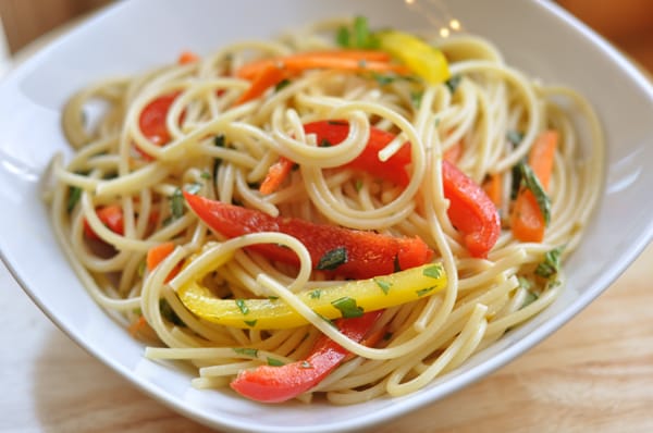 White bowl filled with spaghetti noodles and sliced peppers.