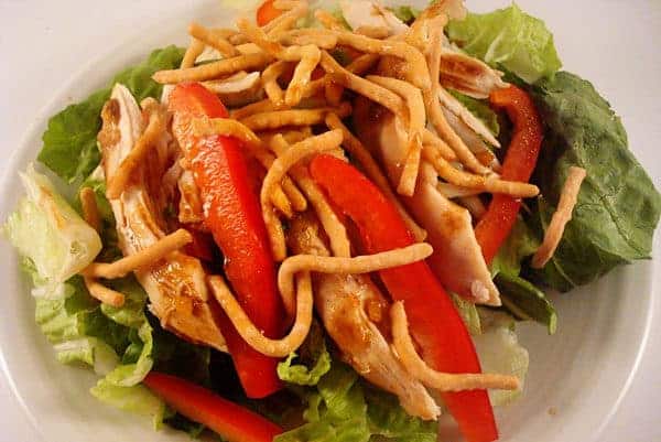 Chicken, pepper strips, and chow mein noodles on a bed of green lettuce.