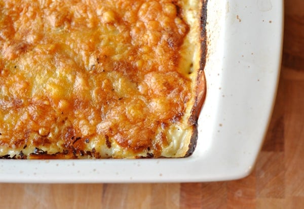 White casserole dish with baked au gratin potatoes topped with golden brown melted cheese.