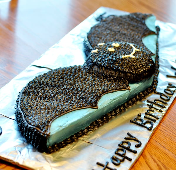 a frosted cute, black bat cake on a tinfoil covered cake board
