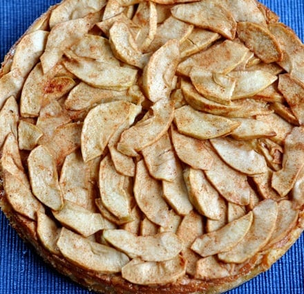 Top view of a circular apple torte with cooked apples lining the top.