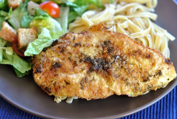 Breaded chicken, salad, and pasta on a brown plate.