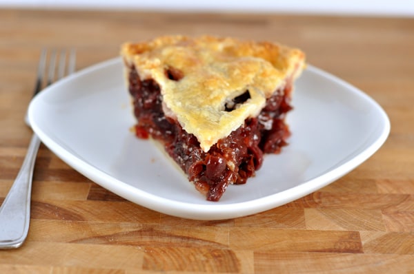 Slice of cherry pie on a white plate.