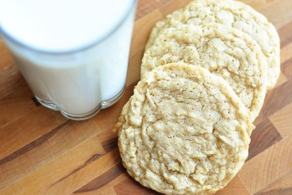 Light brown cookies next to a glass of milk.