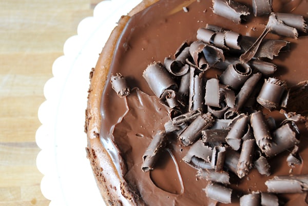 Top view of a chocolate cheesecake with chocolate curls and chocolate ganache on top.