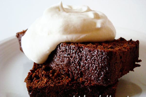 Slice of chocolate gingerbread cake with a dollop of whipped cream on top.