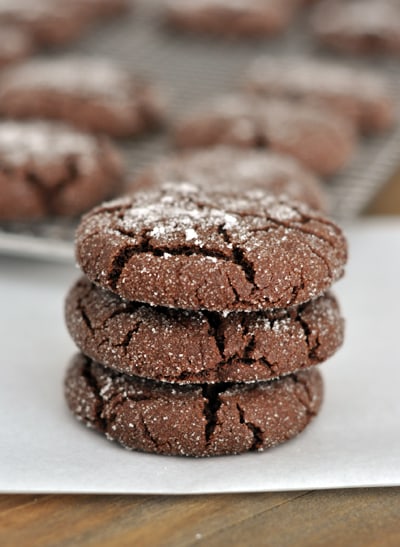Three chocolate sugar cookies stacked on top of each other on a piece of parchment paper.