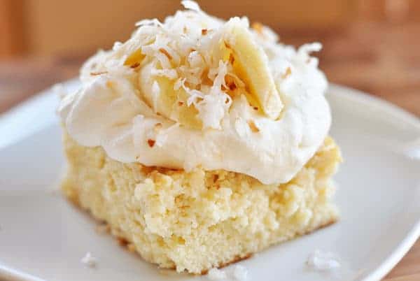 piece of tres leches cake with whipped cream and banana slices on top