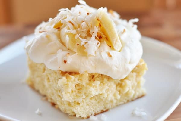 Piece of tres leches cake with whipped cream and banana slices on top.