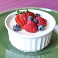 small white ramekin filled with cream and topped with fresh berries
