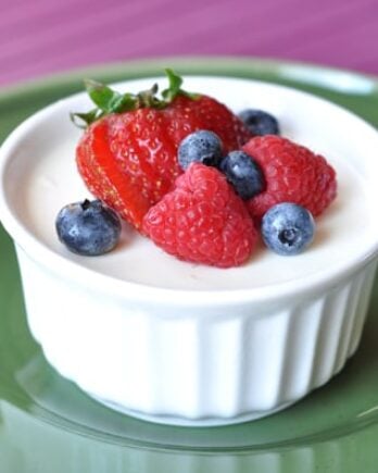 small white ramekin filled with cream and topped with fresh berries