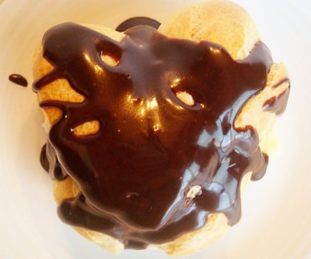 Top view of a heart shaped cream puff covered in chocolate sauce.