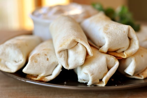 Brown plate stacked with cooked egg rolls.