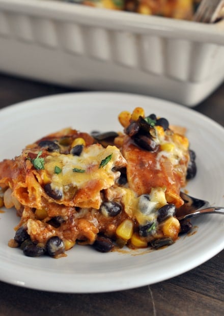 A serving of black bean cheesy enchilada casserole on a white plate.