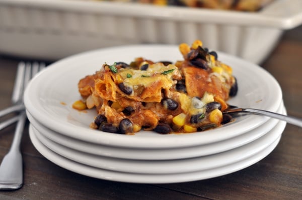 A serving of enchilada casserole and a fork on a white plate.