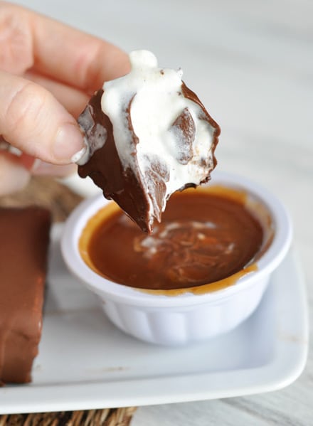 a chocolate ice cream bar half eaten and melting over a bowl of caramel sauce