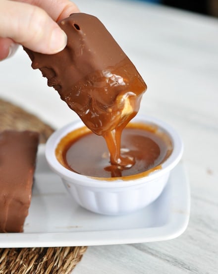 A chocolate coated ice cream bar that was just dipped in a bowl of caramel sauce.