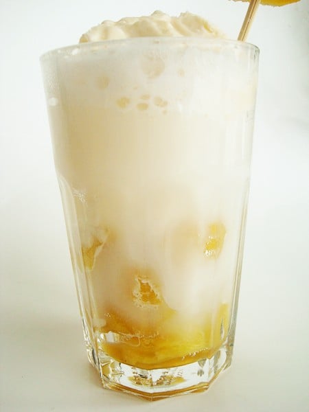 Clear glass cup full of a pineapple ice cream float.