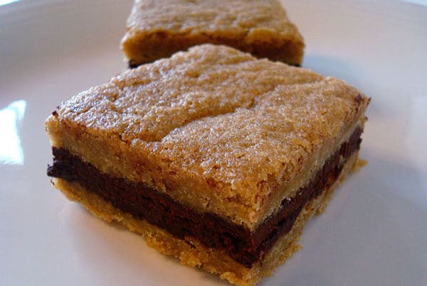 Light brown bar with a dark chocolate middle layer on a white plate.