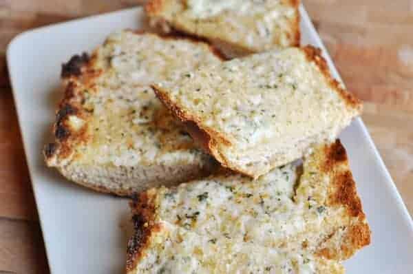 Slices of baked garlic bread on a white plate.