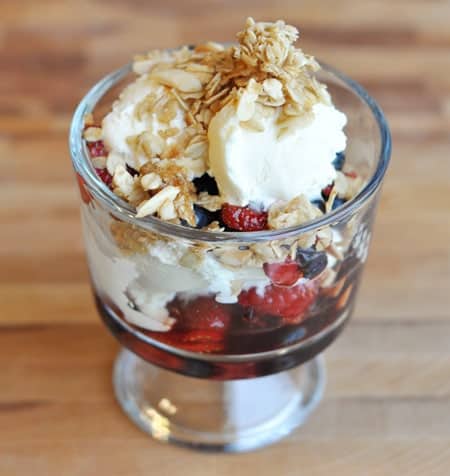 Berry, yogurt, and granola parfait in a glass goblet.