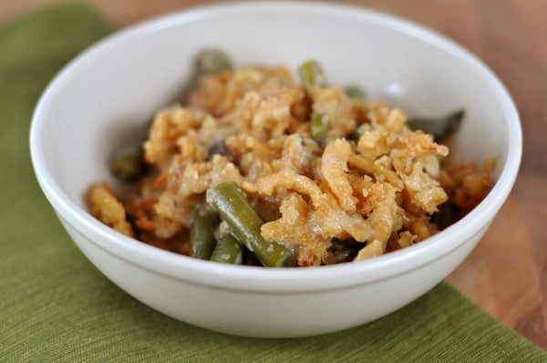 White bowl with green bean casserole topped with fried onions.