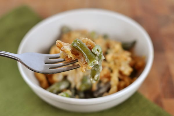 white bowl with green bean casserole, with a fork taking a bite out