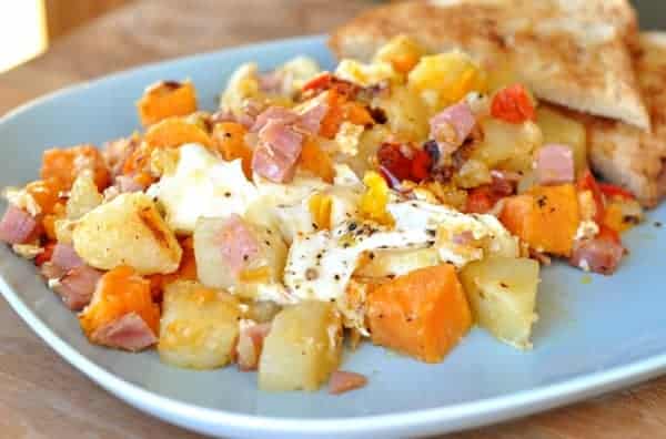 Sweet potato, potato, egg, and ham hash scooped messily on a plate.