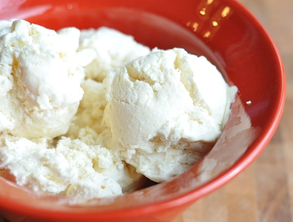 Red bowl with four scoops of vanilla ice cream.