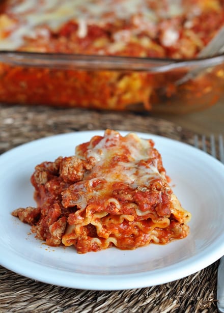 A white plate with a helping of red lasagna.