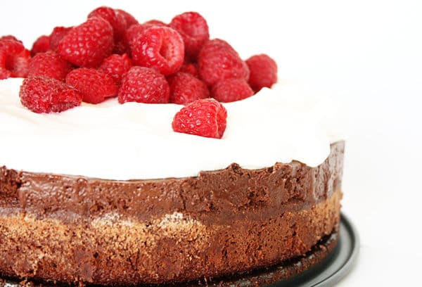 A chocolate torte topped with whipped cream and fresh raspberries.