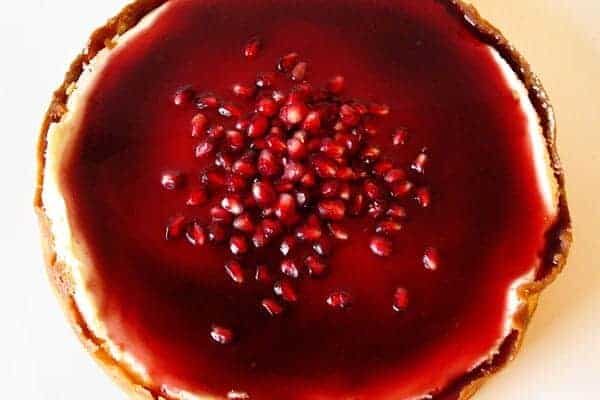 Top view of a cheesecake with pomegranate sauce on top.