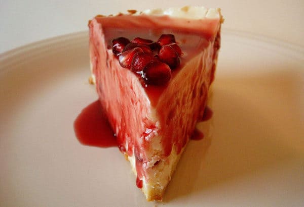 Slice of cheesecake with pomegranate sauce on top.