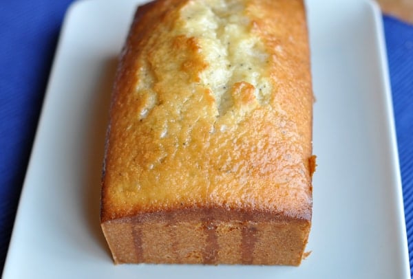 Loaf of glazed poppy seed bread on a white platter.