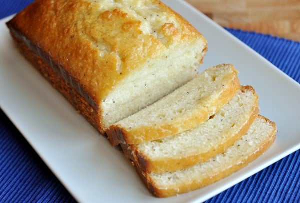 Lemon poppy seed bread with some sliced cut off on a white platter.