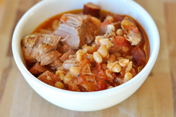chunks of pork, white beans, and a tomato sauce in a white bowl