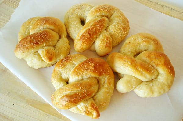 Top down view of four soft, salted pretzels on a white plate.