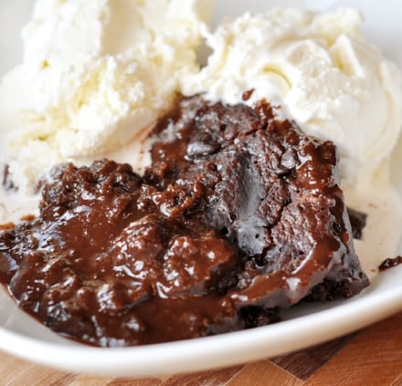 Chocolate pudding cake and vanilla ice cream in a white bowl.