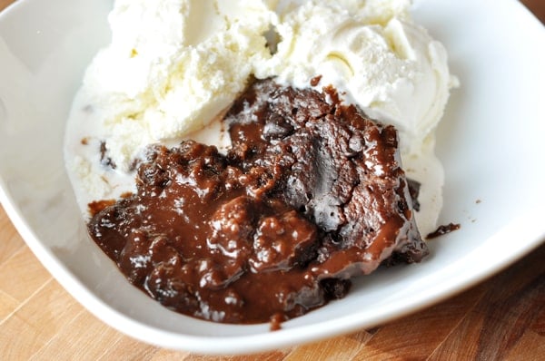 White bowl full of chocolate pudding cake and vanilla ice cream.